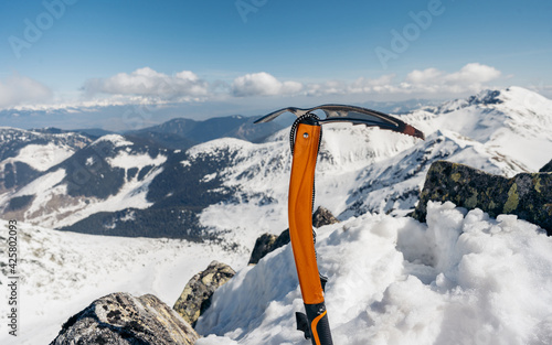 Mountain climbing pick axe in the snow. Ice axe in the snow against the background of the mountains photo