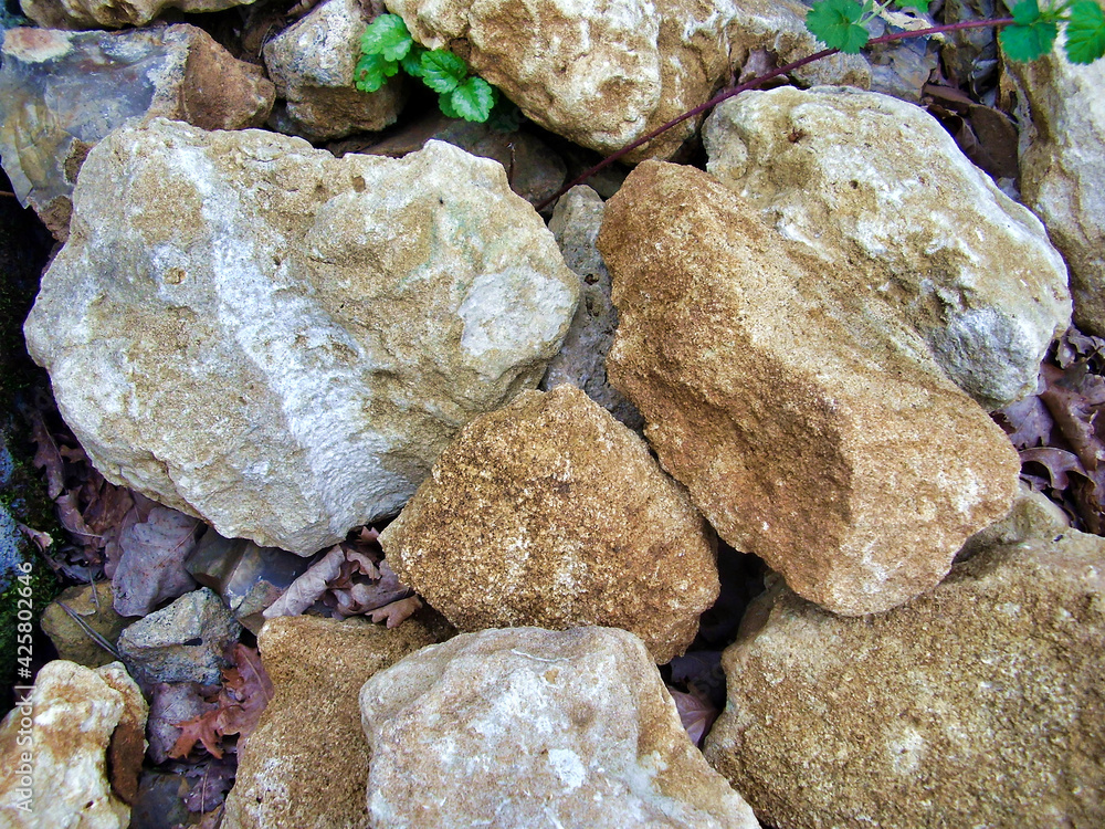 Pile of limestone and sandstone rocks stored in a garden to use as hardcore or as wall repairs.
