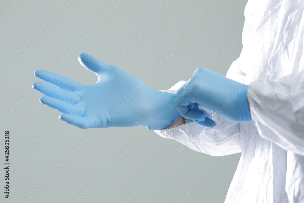 Doctor in a protective suit puts on blue rubber gloves Doctor in a protective suit puts on blue rubber gloves