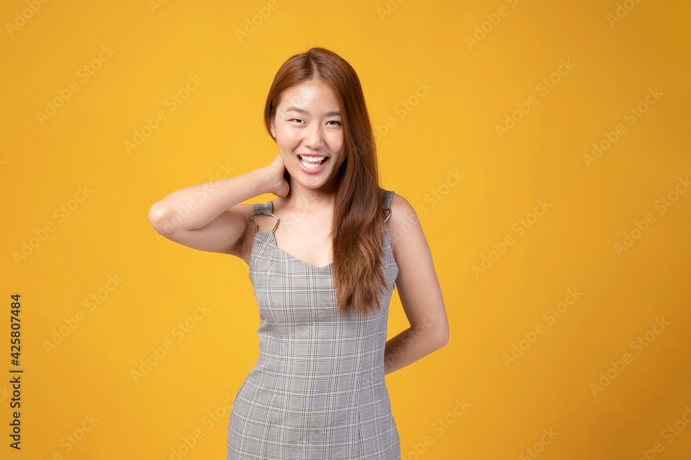 Asian girl on yellow background. Attractive young girl with happy emotion with copy space. Happy smiling young Asian girl isolated on yellow studio background. Carefree happy Asian girl. Asian girl on yellow background. Attractive young girl with happy emotion with copy space. Happy smiling young Asian girl isolated on yellow studio background. Carefree happy Asian girl.