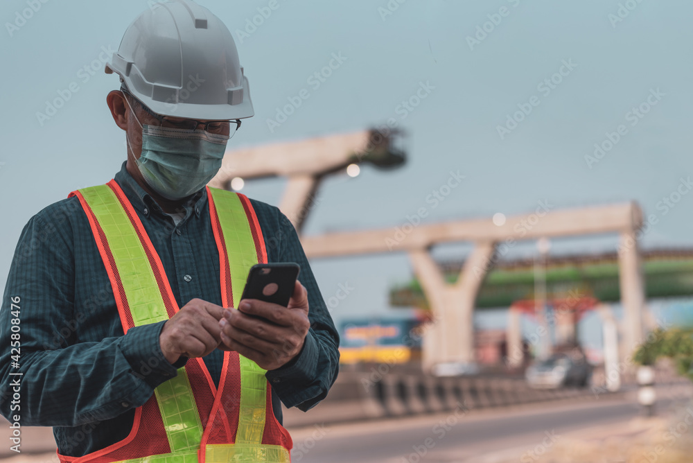 Portrait of engineers using smartphones in the workplace. Senior engineers wearing helmets and using cellphone on the construction site