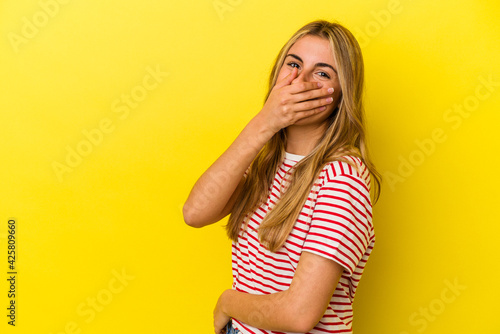 Young blonde caucasian woman isolated on yellow background laughing happy, carefree, natural emotion.