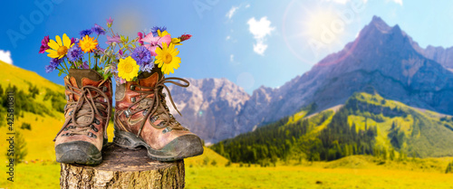 walking boots with flowers in beautiful rural landscape