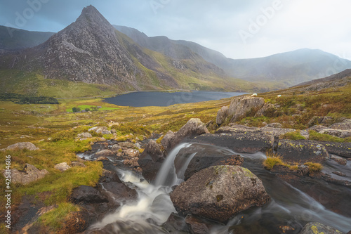 Moody, dramatic landscape of waterfall with Tryfan peak and Llyn Ogwen and valley in Snowdonia National Park, North Wales.