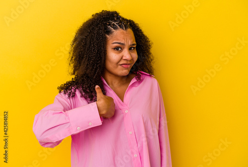 Young african american woman isolated on yellow background surprised pointing with finger, smiling broadly.