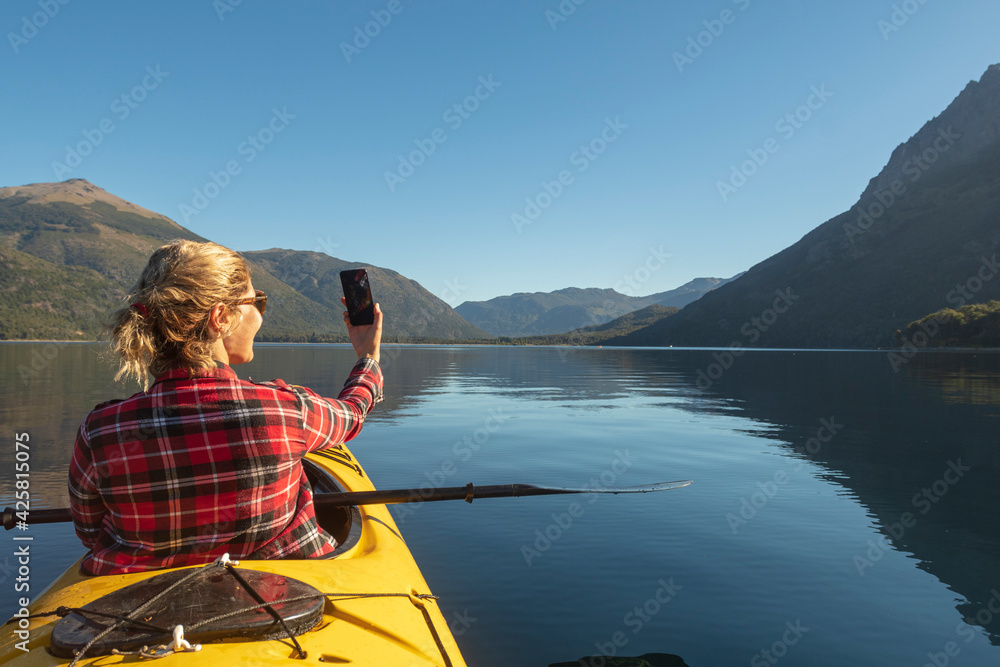 Beautiful young woman taking a selfie from her kayak to share her beautiful vacations on her social networks.