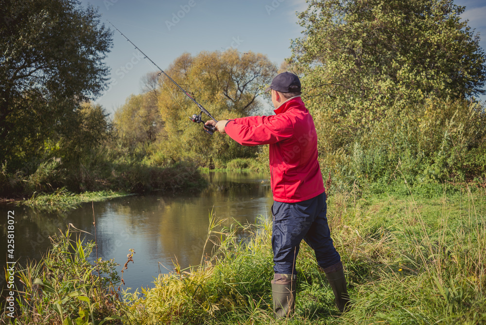 Fishermen fishing with a spinning rod from the shore on a sunny day. Fishing on a sunny day. Man on the river bank throws a spinning rod. Fishermen fishing with a spinning rod from the shore on a sunny day. Fishing on a sunny day. Man on the river bank throws a spinning rod.