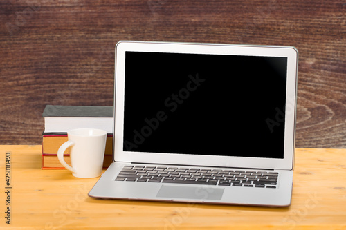 Laptop with blank screen, cup of coffee and books or notebooks on a wooden table. mockup for your text.home education concept