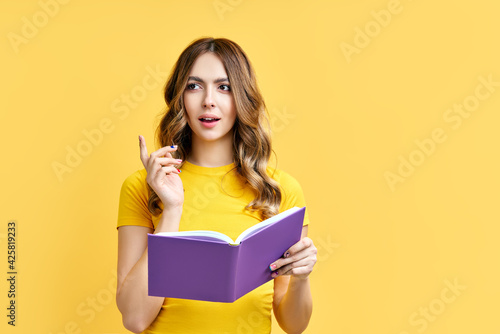 Dreamy positive girl rest with book on yellow background with copy space