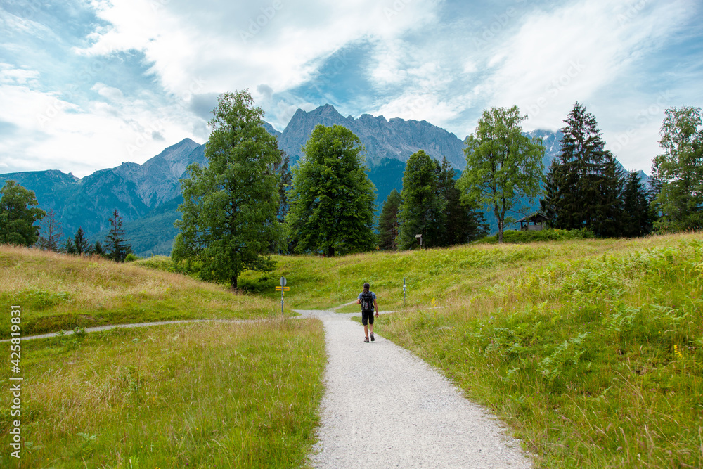 Back view of Traveler, Backpacker walking and enjoy nature. Mountain range wetterstein mountains, Waxenstein and Zugspitze peaks. Wetterstein range Northern Limestone Alps Bayern Germany Europe