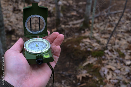 Hand raising prismatic compass on a trail
