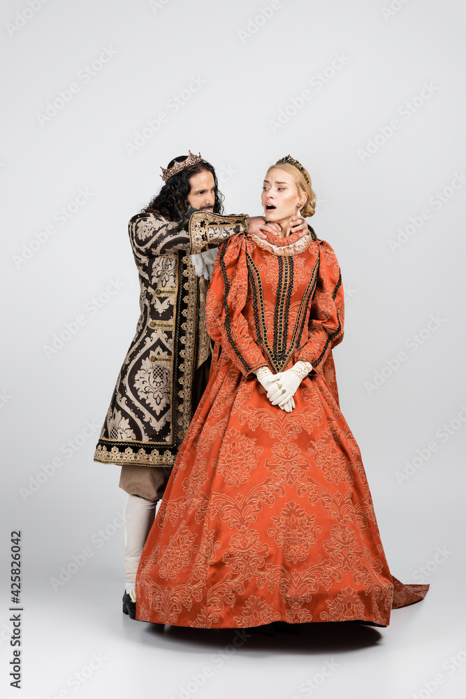 full length of hispanic king in medieval clothing choking shocked queen in crown on white full length of hispanic king in medieval clothing choking shocked queen in crown on white