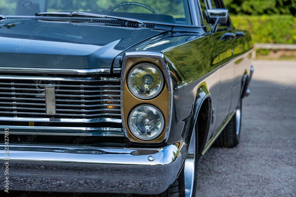 Close up of the front headlights of a classic car from the sixties