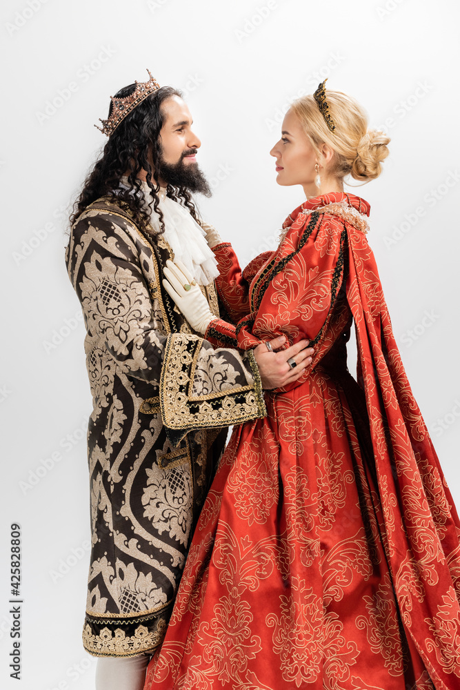 interracial king and queen in medieval clothing and crowns hugging isolated on white