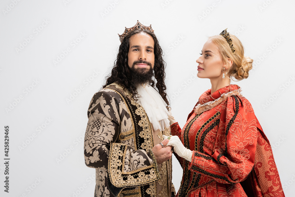 historical interracial couple in crowns and medieval clothing holding hands isolated on white