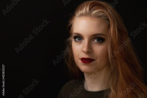 Low key portrait of smiling redhead young woman. Horizontally. 