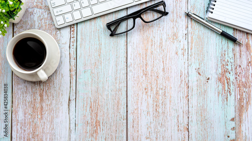 Top view wooden table coffee mug keyboard glasses notebook place copy space.