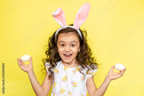 funny happy girl with easter bunny ears on yellow background