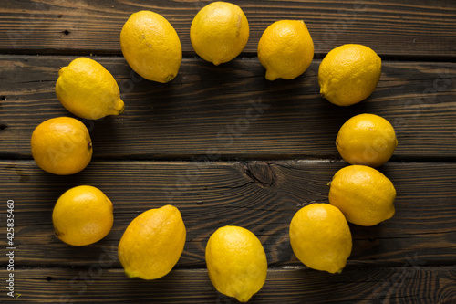 Circle of yellow fresh lemons on a wooden background. photo