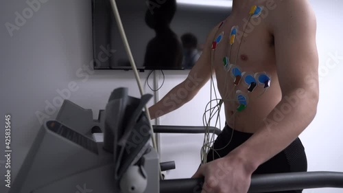 Unrecognizable man walking on treadmill during cardiac stress test photo