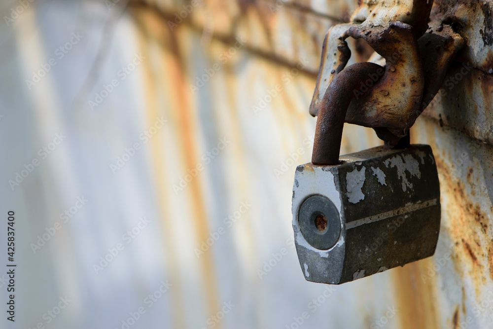Rusty old padlock on metal gate closeup. Dirty lock on closed Grey painted front door. Protection, security and safety concept. Private property entrance. old rusty iron texture. space for text Rusty old padlock on metal gate closeup. Dirty lock on closed Grey painted front door. Protection, security and safety concept. Private property entrance. old rusty iron texture. space for text
