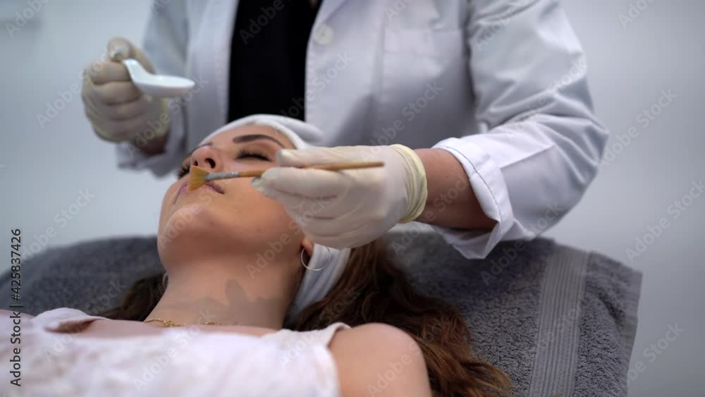 Crop beautician applying acid peeling on face of woman Crop beautician applying acid peeling on face of woman