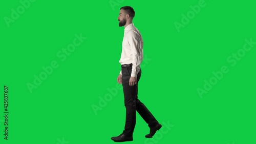 Side view of successful confident business man walking. Full length on green screen chroma background.