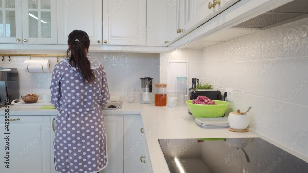 Woman cooking dinner in modern white clean kitchen, home interior. High quality 4k footage Woman cooking dinner in modern white clean kitchen, home interior. High quality 4k footage