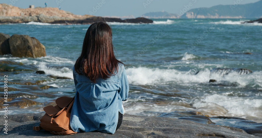 Woman sit on the rock and enjoy the sea view
