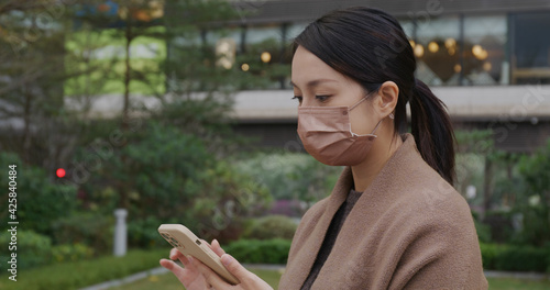 Woman wear face mask and use of mobile phone at park