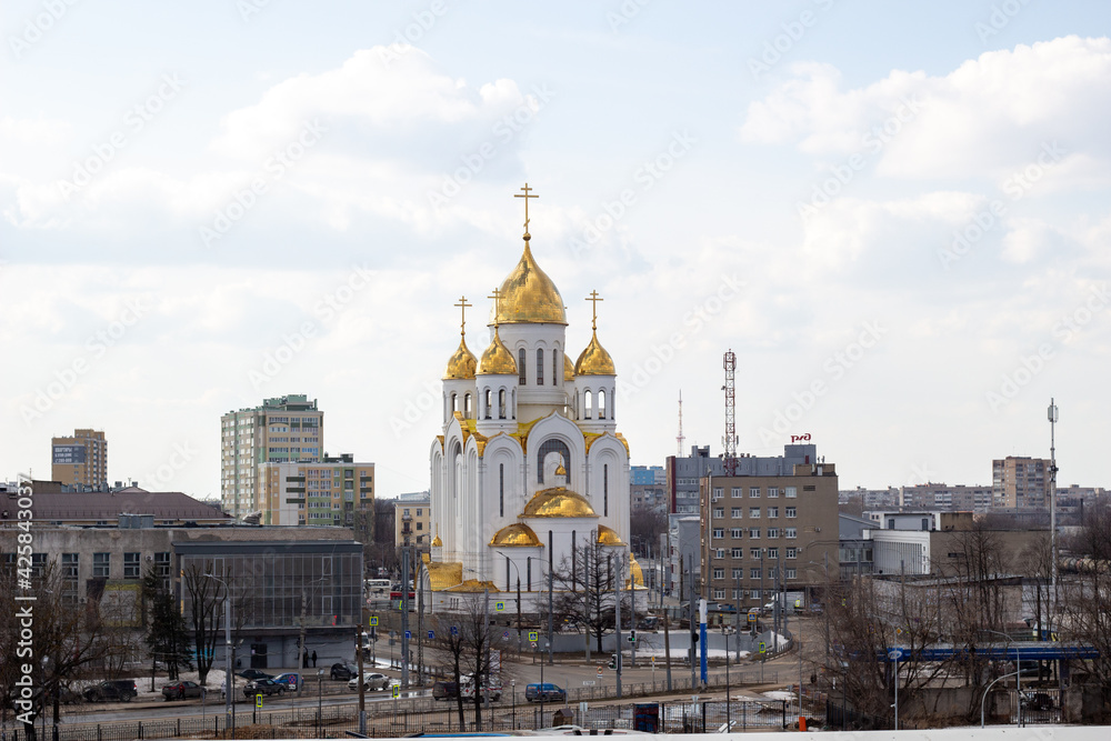 Cityscape on hilly bike park, street, buildings, Golden shining domes of white church in blue sky with clouds in Ivanovo, Russia