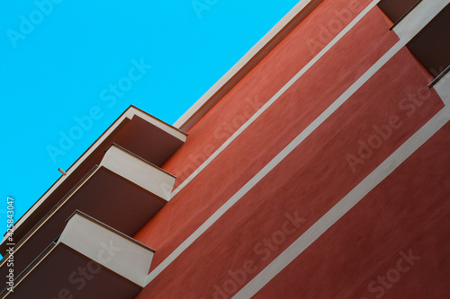 Urban construction, detail of residential building with balconies, dark red and gray plaster