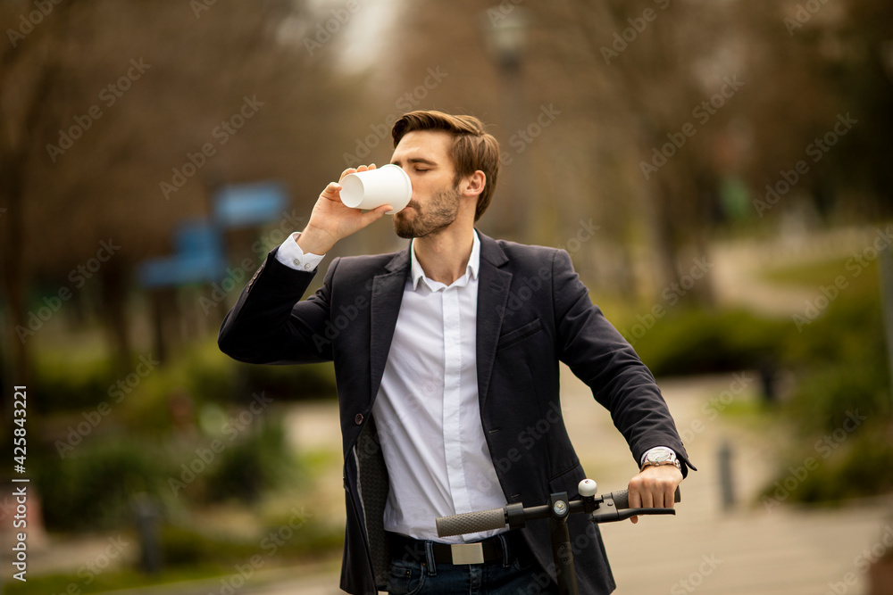 Young businessman with take away coffee cup on electric scooter Young businessman with take away coffee cup on electric scooter