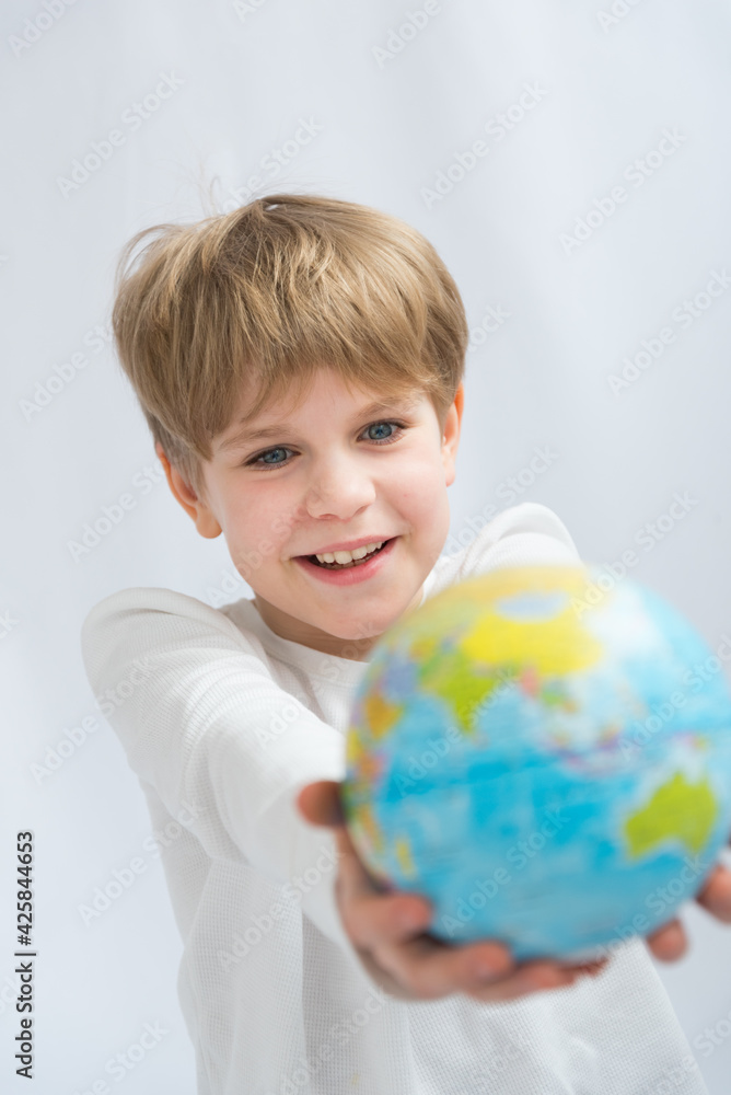 Happy laughing child holding a globe in front of him. Travel happiness concept. The anticipation of a vacation or vacation. Buying a tour. Opening borders after quarantine Happy laughing child holding a globe in front of him. Travel happiness concept. The anticipation of a vacation or vacation. Buying a tour. Opening borders after quarantine