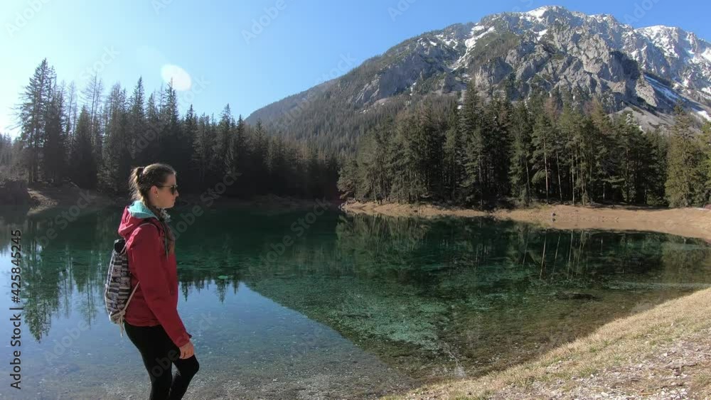 A woman in pink jacket walking along the shore of the Green Lake in Austria. The lake is surrounded by high Alps and dense forest, reflecting in the lake's surface. Meditation in the nature. Calmness
A woman in pink jacket walking along the shore of the Green Lake in Austria. The lake is surrounded by high Alps and dense forest, reflecting in the lake's surface. Meditation in the nature. Calmness