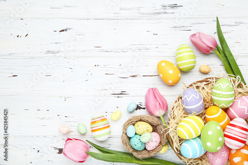 Photography Colorful easter eggs with tulip flowers on white wooden background