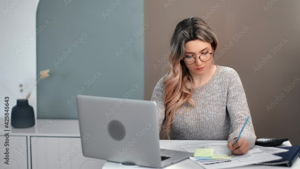 Focused female in glasses studying e learning use laptop writing notes. Shot with RED camera in 4K Focused female in glasses studying e learning use laptop writing notes. Shot with RED camera in 4K