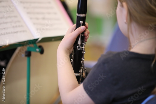  View from the back of a little girl with a musical instrument clarinet with notes in a music lesson at school.Selective focus.The concept of children's creativity photo