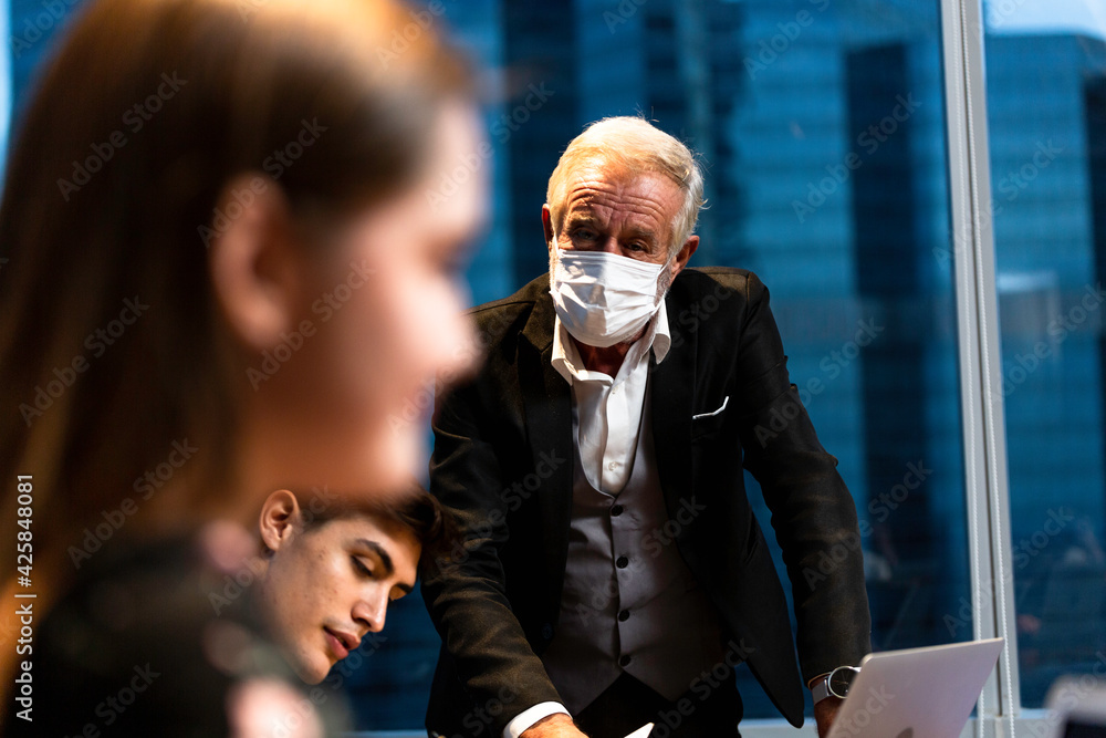 Senior boss in protective mask discussing and brainstorming with employee in meeting room. business people working overtime during Coronavirus Senior boss in protective mask discussing and brainstorming with employee in meeting room. business people working overtime during Coronavirus