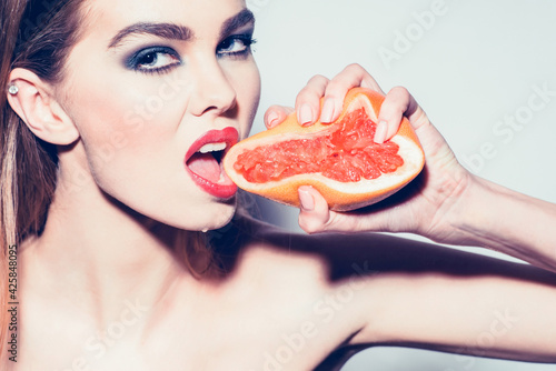 Pretty girl or sexy woman squeezing juice from fresh orange grapefruit, Summer citrus fruit with hand.