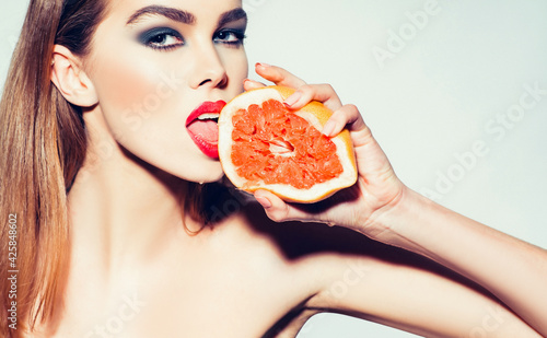 Sensual woman lick juice from fresh orange grapefruit, Summer citrus fruit with hand.