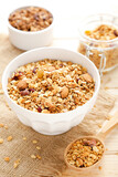 Tasty granola in bowl and spoon on brown wooden background