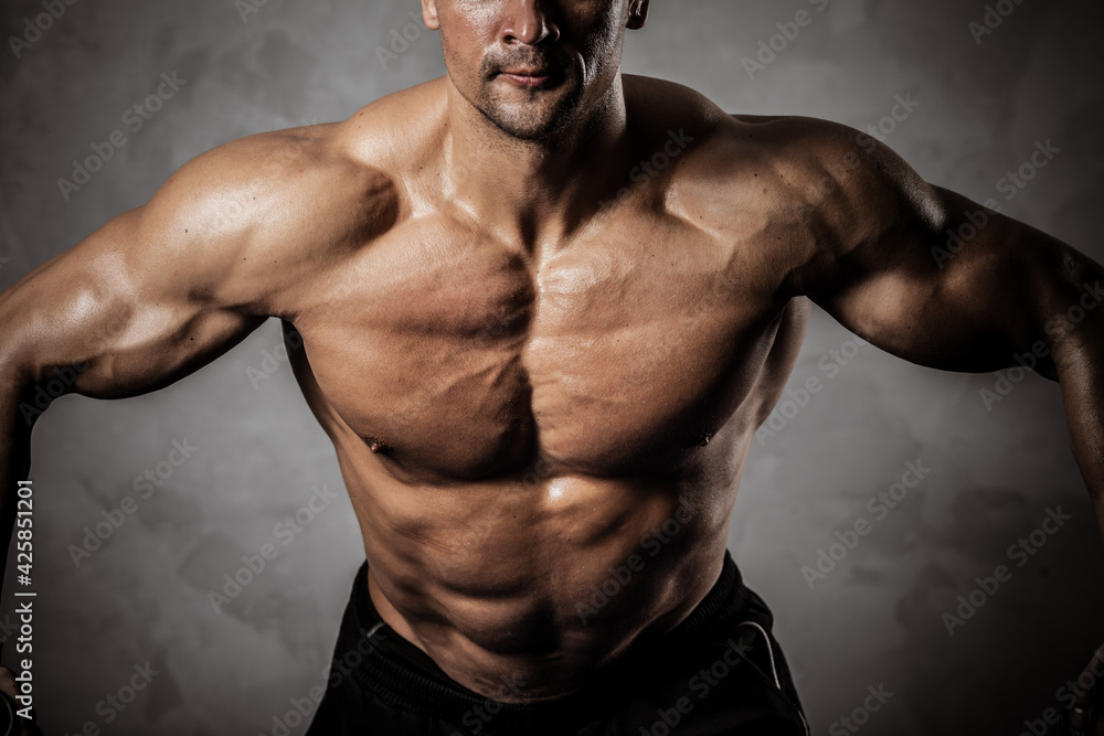 Fitness in gym, sport and healthy lifestyle concept. Handsome athletic man with naked torso making exercises. Bodybuilder male model pumping up muscles on crossover training apparatus Fitness in gym, sport and healthy lifestyle concept. Handsome athletic man with naked torso making exercises. Bodybuilder male model pumping up muscles on crossover training apparatus