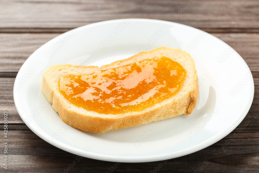 Toast with apricot jam in plate on wooden table Toast with apricot jam in plate on wooden table