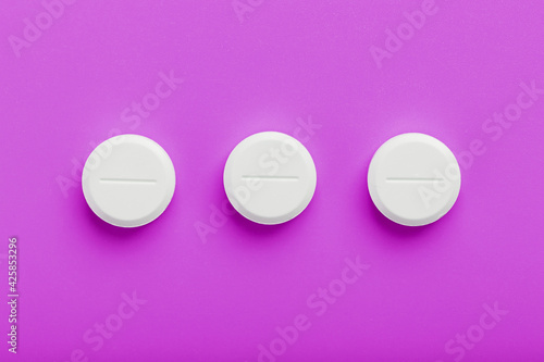 White Ecstasy pills in a row on a pink background, isolate.