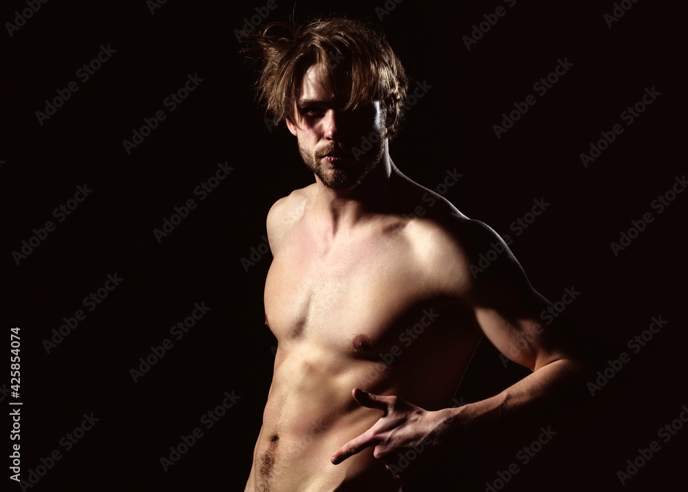 Sexy man showing sexy muscular torso. Portrait of handsome man in studio on dark background.