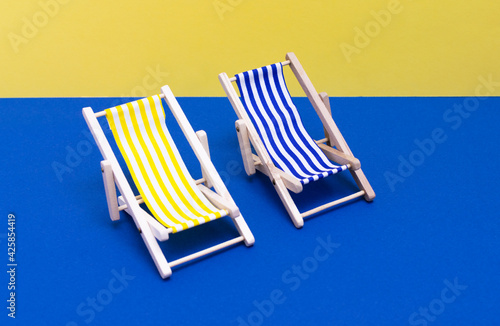 
Wooden blue, yellow and white striped hammock chairs on plain blue and yellow isolated background, close up view.