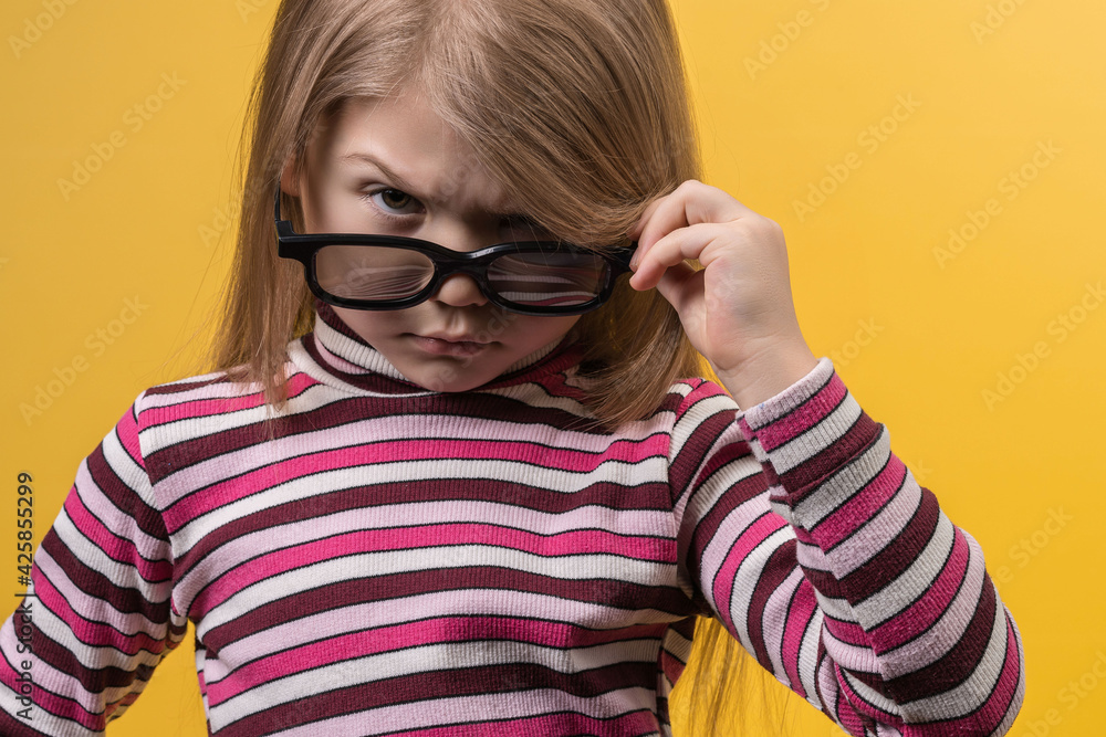 Children's cinema concept. White girl in 3D glasses with different emotions on a yellow background. Children's cinema concept. White girl in 3D glasses with different emotions on a yellow background.