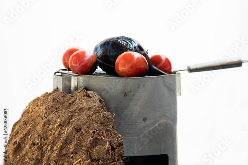 Rural Desi India Cooking Concept - Cooking Brinjal Baingan Ka Bharta On Traditional Chulha Or Shegadi Using Biodegradable Pure Organic Cow Dung Cake Gobar Ke Uple. White Background With Copy Space photo