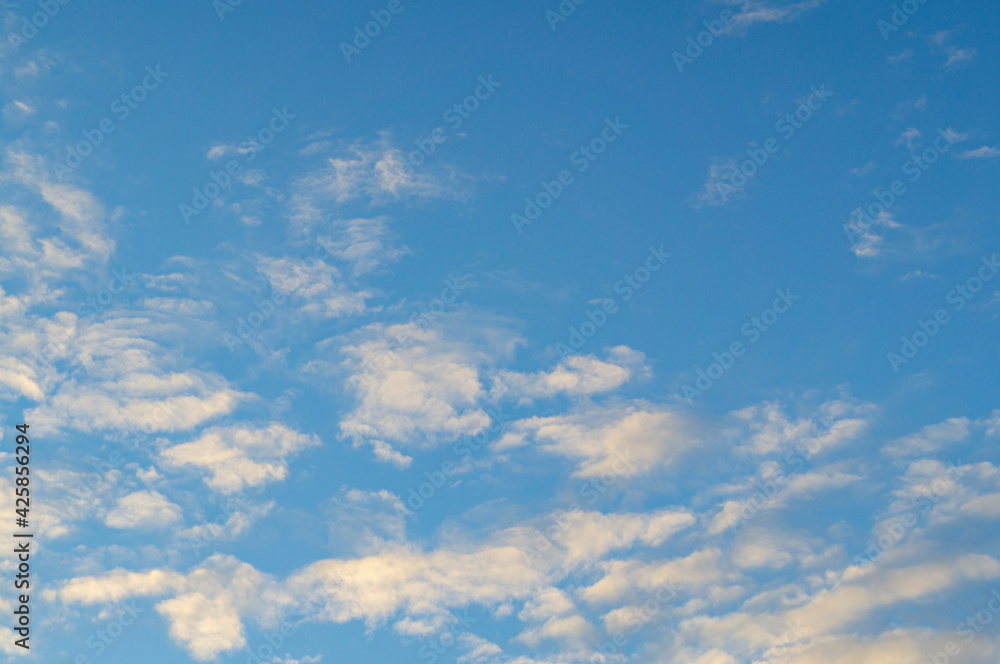 Blue sunny sky with white contrasting clouds for background